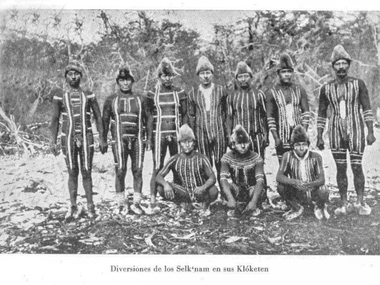 Grupo de hombres selk'nam reunidos en la celebración de un Kloketen, con rostros y cuerpos pintados según la costumbre